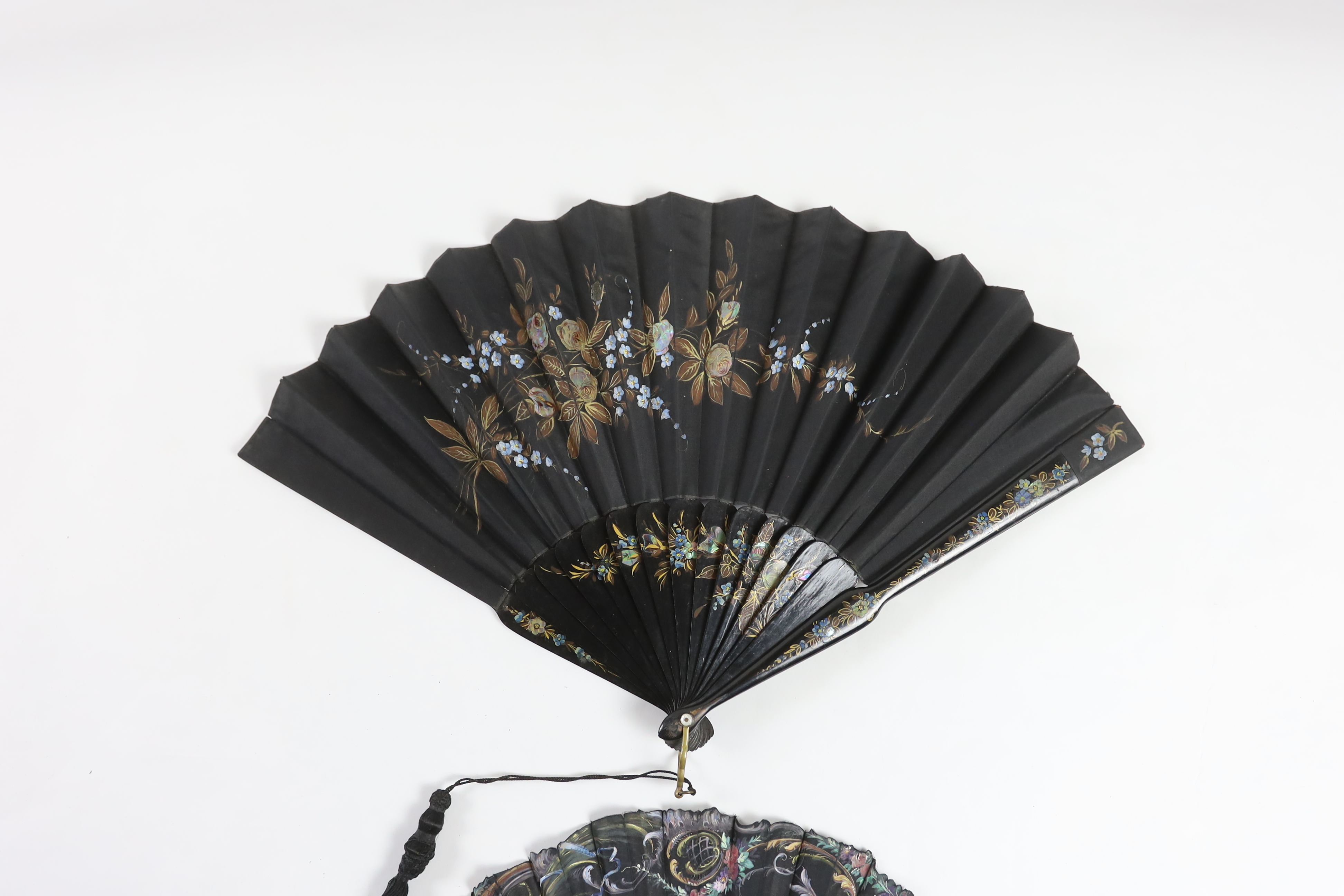 A late 19th century hand painted shaped and carved figurative fan, signed, together with a lacquer and mother of pearl fan, with matching leaf and guard decoration